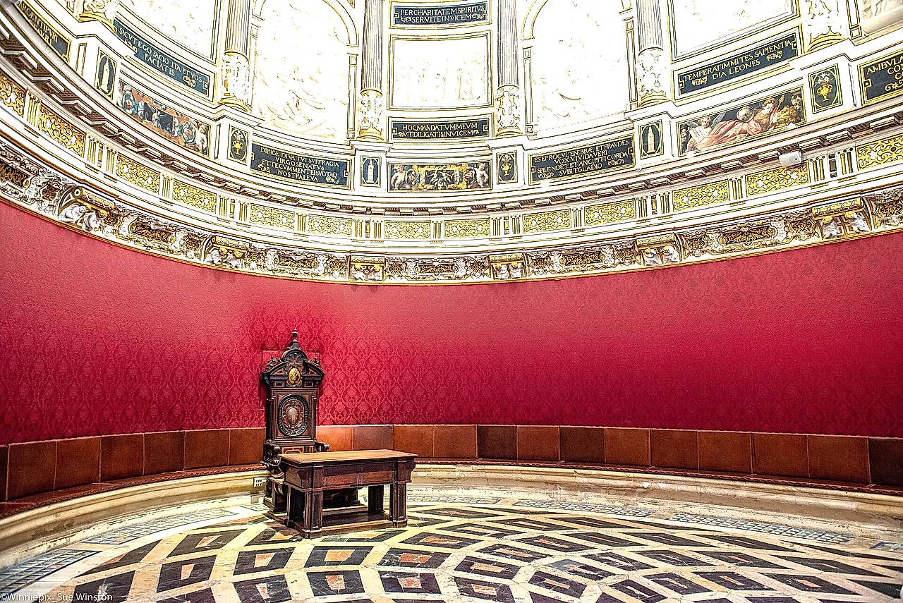 La Sala Capitolare ellittica con le pareti rosse e il pavimento in marmo
